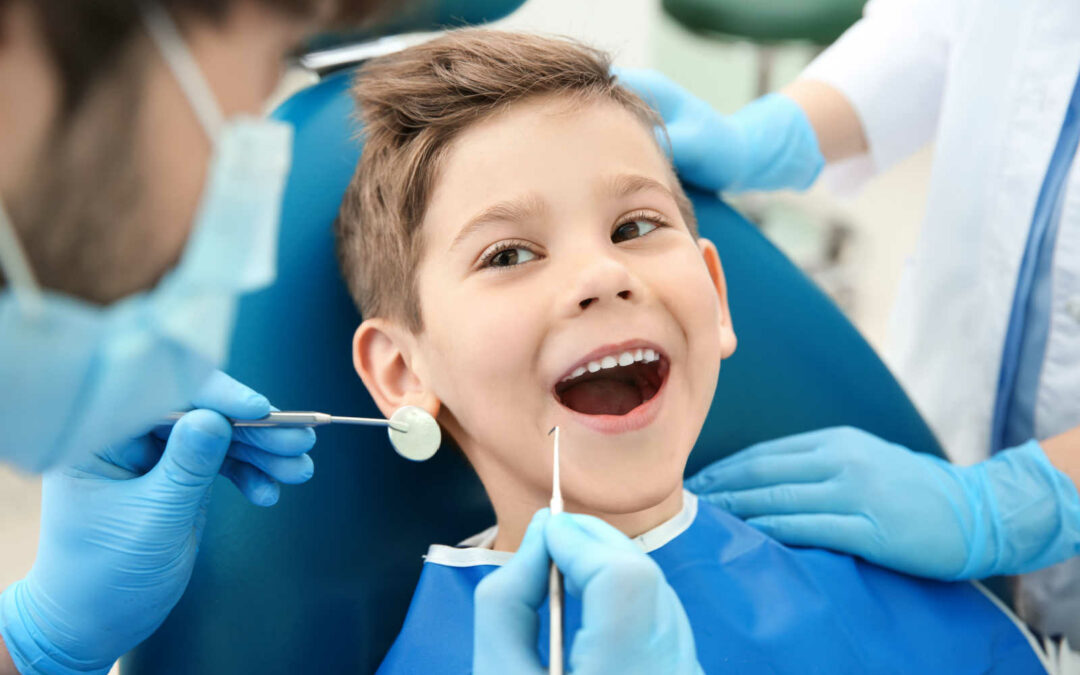 A young boy sitting in a dentist chair getting his teeth checked by his dentist.