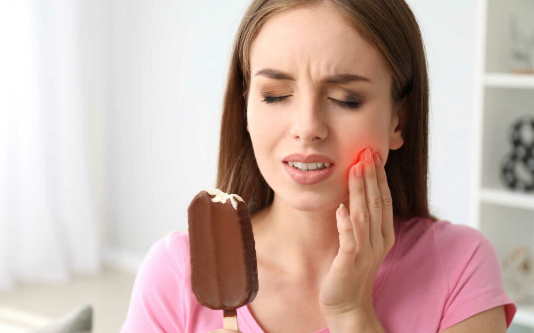 A young woman trying to eat ice cream while experiencing severe tooth sensitivity due to cold.